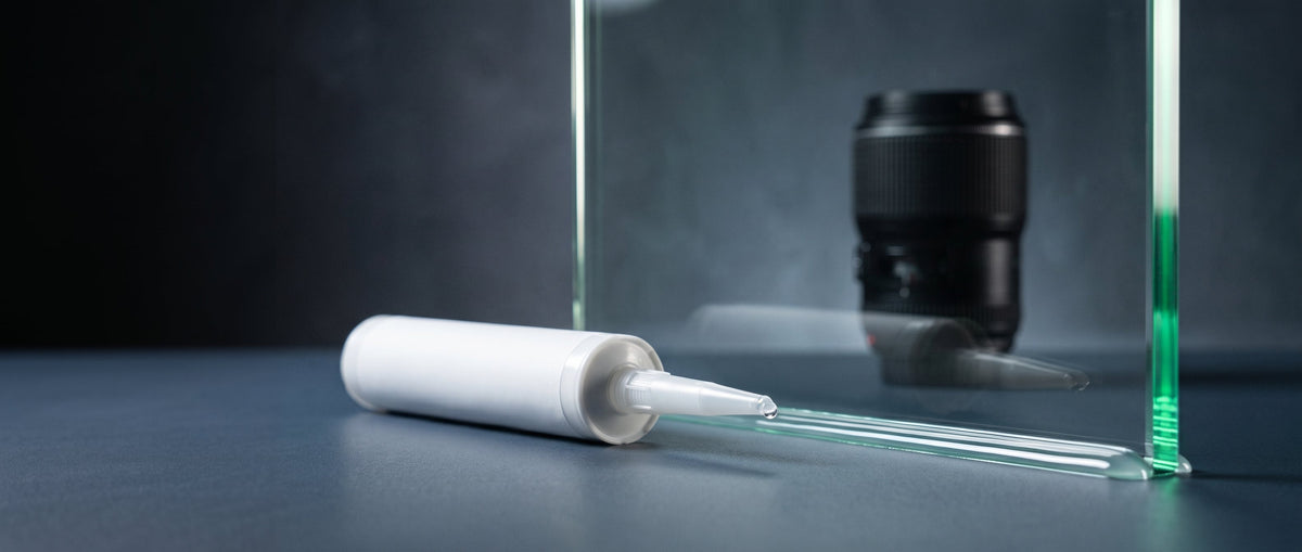 Transparente Silikonfuge an der Glaskante mit Dichtstoff-Kartusche